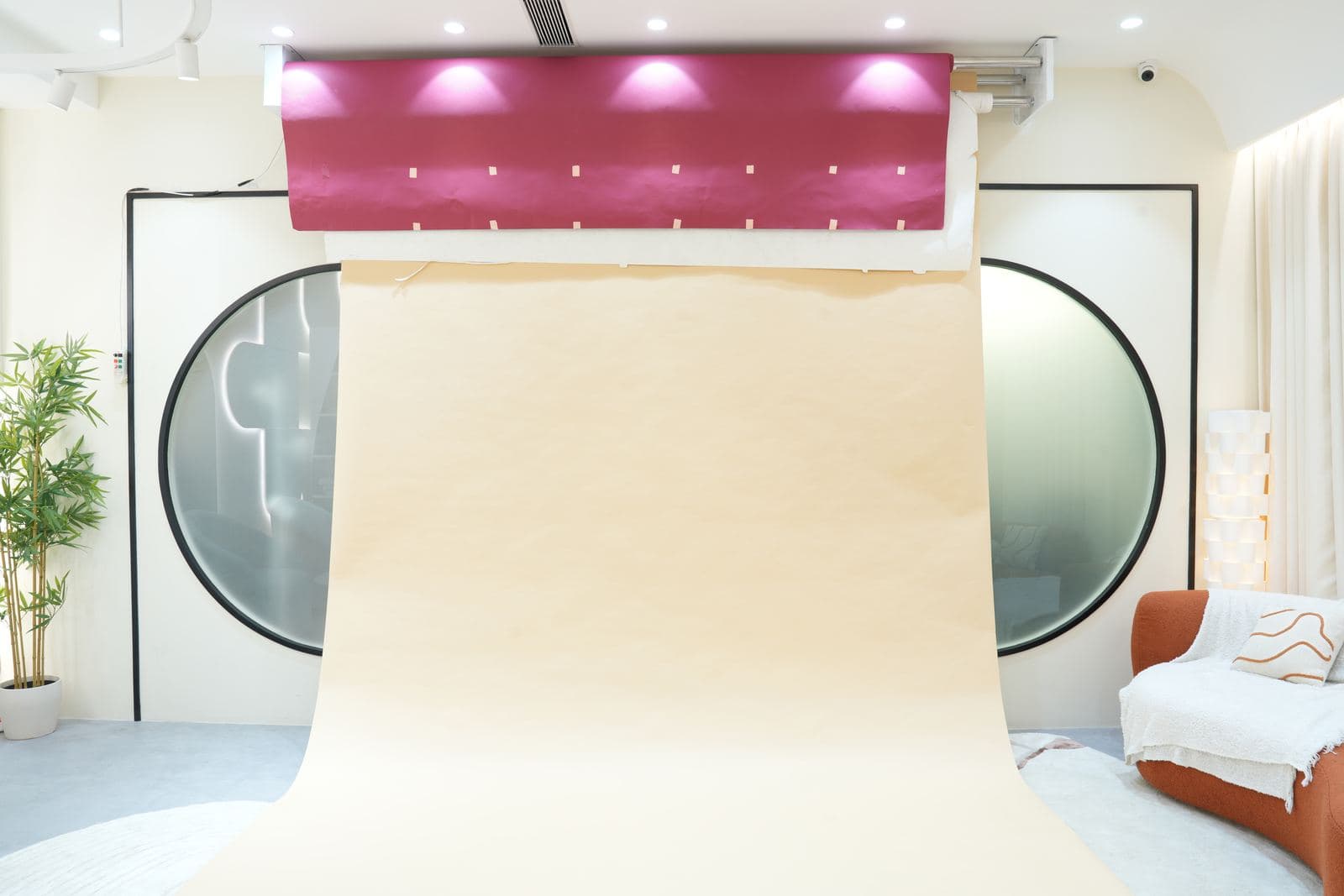 The plain backdrop set: a seamless paper backdrop rigged under a pink lighting strip, hung in front of the two round mirror sliding doors with the living room chair to one side.