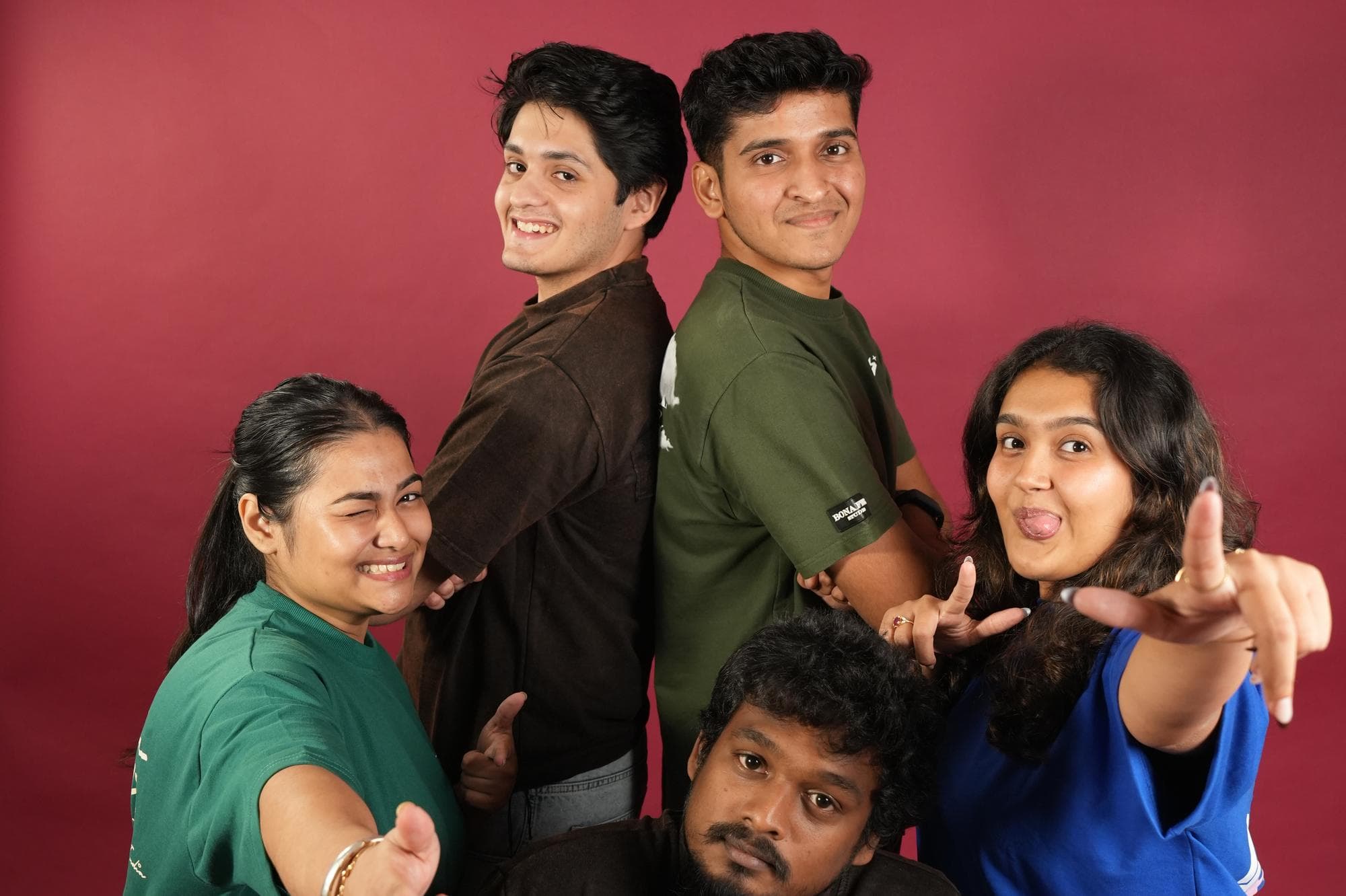 The five-person Endura Studios team together against the maroon backdrop